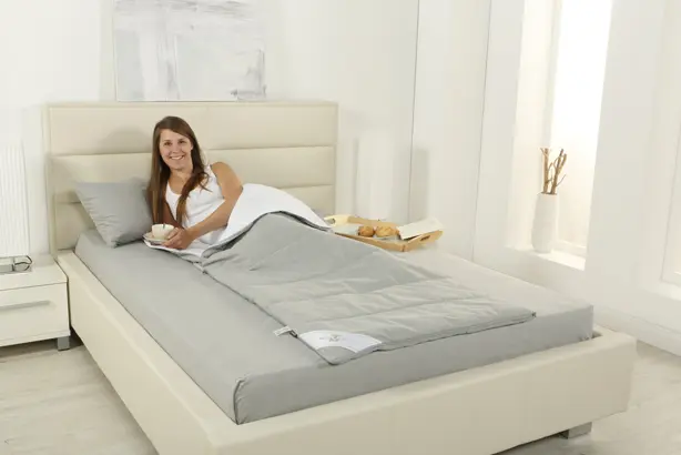 Eine Frau liegt in einem grauen Schlafsack der Serie PULMANOVA von MEDI-TECH auf einem beige-farbigen Bett.